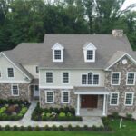 A large stone and brick house with two dormer windows and a chimney.