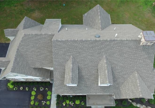 Aerial view of a gray rooftop with two dormer windows.